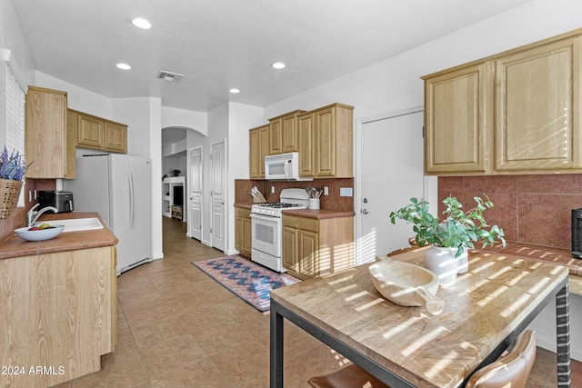 kitchen with sink, backsplash, white appliances, light brown cabinetry, and light tile patterned floors