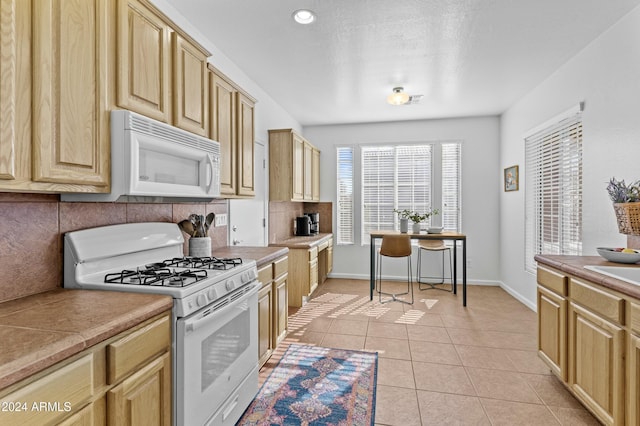 kitchen with decorative backsplash, light brown cabinets, white appliances, and light tile patterned floors