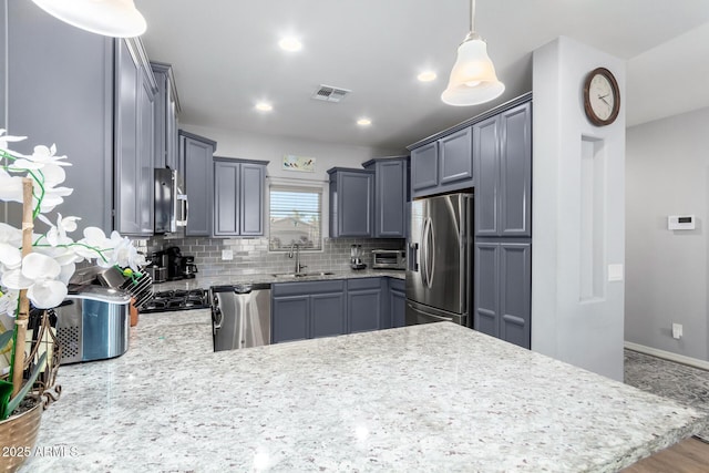 kitchen featuring gray cabinets, stainless steel appliances, tasteful backsplash, decorative light fixtures, and sink