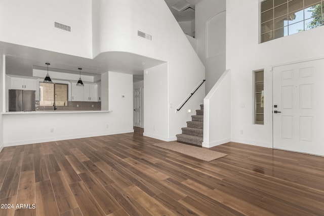 unfurnished living room featuring sink, hardwood / wood-style flooring, and a high ceiling