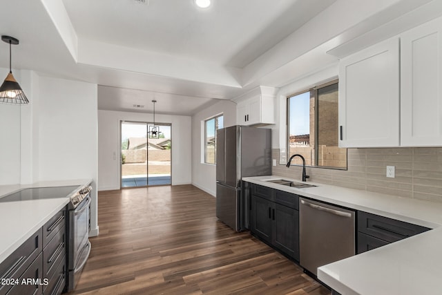 kitchen with white cabinetry, dark wood-type flooring, dishwasher, decorative light fixtures, and tasteful backsplash