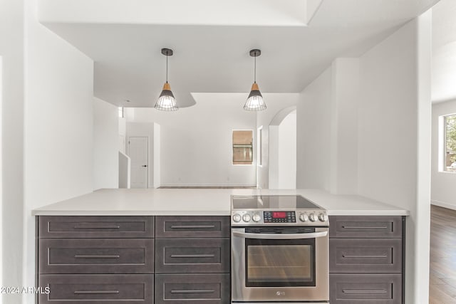 kitchen with stainless steel range with electric stovetop, hanging light fixtures, hardwood / wood-style floors, and dark brown cabinetry