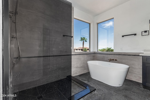 bathroom with tile patterned floors, vanity, tile walls, and tiled shower