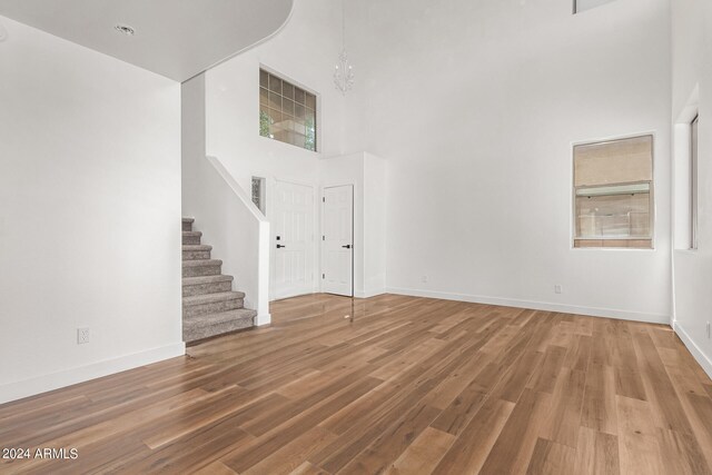 unfurnished living room with a towering ceiling, hardwood / wood-style floors, and an inviting chandelier