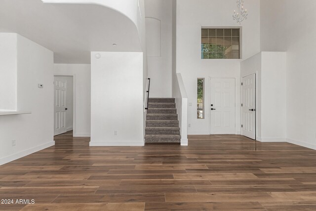 foyer with a notable chandelier, wood-type flooring, and a high ceiling