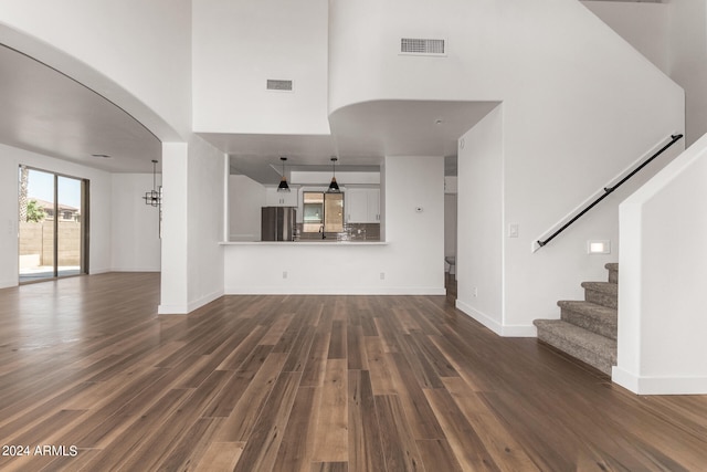 unfurnished living room featuring a towering ceiling and hardwood / wood-style flooring