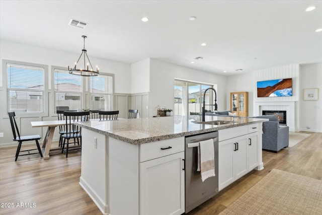 3919 W Abalone Ln, San Tan Valley, AZ 85144 - kitchen with a sink, stainless steel dishwasher, a glass covered fireplace, a center island with sink, and a chandelier