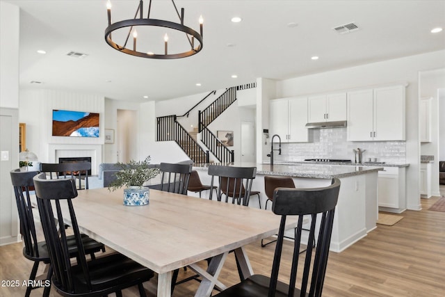 3919 W Abalone Ln, San Tan Valley, AZ 85144 - dining room with a warm lit fireplace, light wood-style floors, recessed lighting, and a chandelier