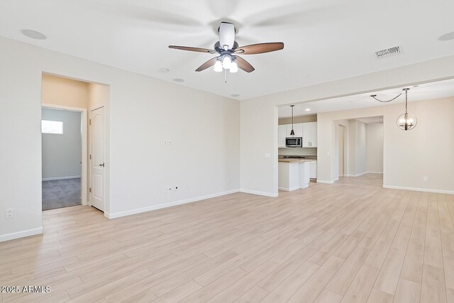 12727 W Lowden Rd, Peoria, AZ 85383 - unfurnished living room with ceiling fan, light wood-style floors, and baseboards