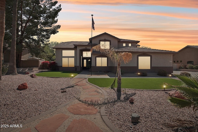 view of front facade with a lawn and stucco siding