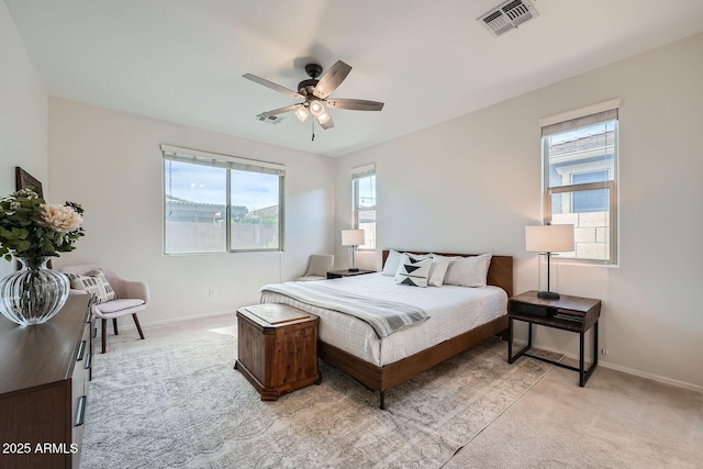 bedroom featuring baseboards, visible vents, light colored carpet, and ceiling fan