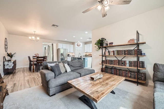 living area with recessed lighting, visible vents, light wood-type flooring, baseboards, and ceiling fan with notable chandelier
