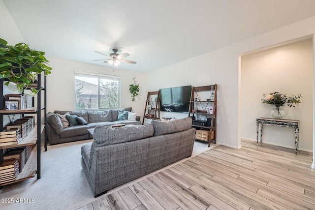 living area with light wood-style floors, a ceiling fan, and baseboards