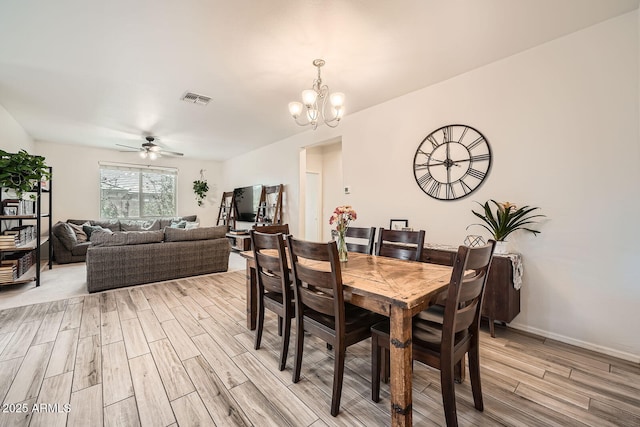 dining space with ceiling fan with notable chandelier, light wood-style flooring, and visible vents