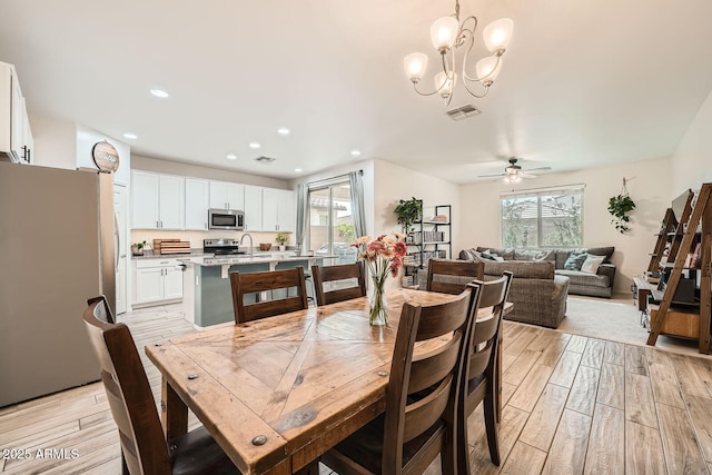 dining room with light wood-style floors, a wealth of natural light, and ceiling fan with notable chandelier