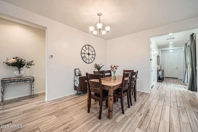 dining space featuring light wood finished floors, baseboards, a chandelier, and visible vents