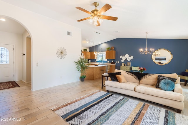 living area featuring arched walkways, lofted ceiling, ceiling fan with notable chandelier, visible vents, and light wood-style floors