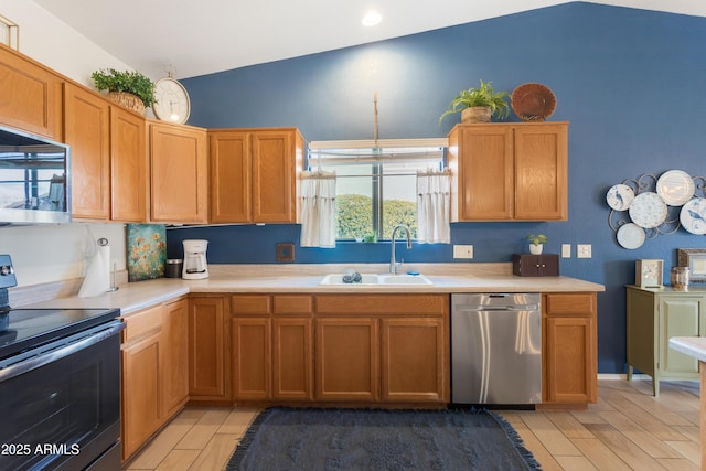 kitchen with appliances with stainless steel finishes, wood tiled floor, light countertops, and a sink