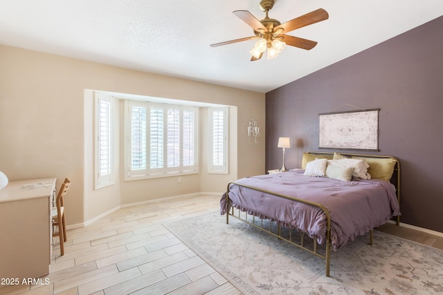 bedroom featuring a ceiling fan, vaulted ceiling, baseboards, and wood finished floors