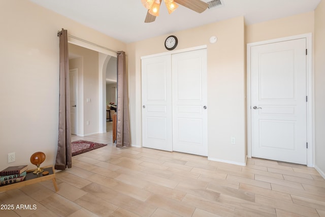 unfurnished bedroom with arched walkways, wood finish floors, a closet, and baseboards