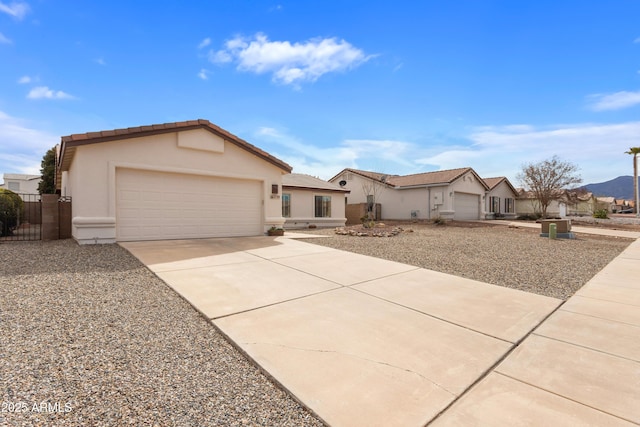 single story home with stucco siding, concrete driveway, an attached garage, fence, and a tiled roof