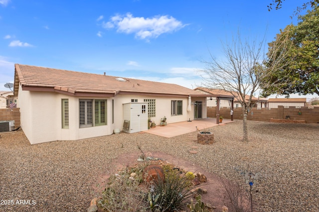 back of property featuring a patio, an outdoor fire pit, central AC, fence, and stucco siding