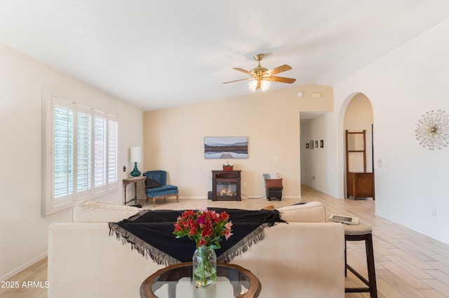 living room with lofted ceiling, light wood finished floors, arched walkways, and a ceiling fan