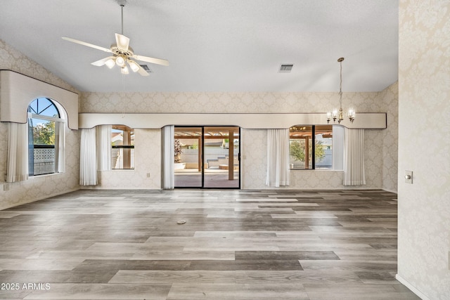 interior space with ceiling fan with notable chandelier, wood-type flooring, vaulted ceiling, and a healthy amount of sunlight