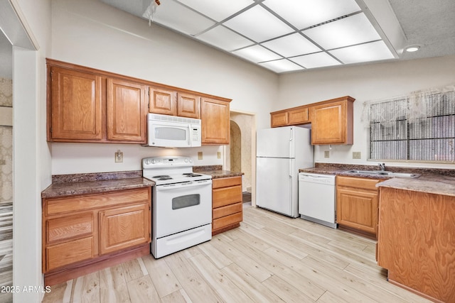 kitchen with sink, white appliances, light hardwood / wood-style flooring, and lofted ceiling