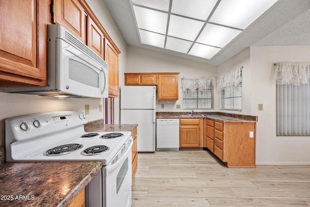 kitchen with sink, white appliances, and lofted ceiling