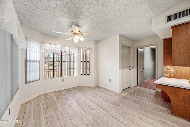 interior space featuring ceiling fan, light hardwood / wood-style flooring, and a textured ceiling