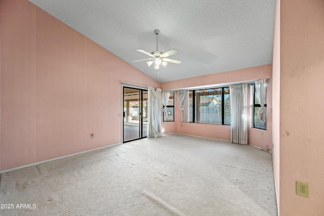 carpeted spare room featuring a textured ceiling, vaulted ceiling, and ceiling fan