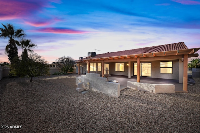 back house at dusk with central air condition unit and a patio