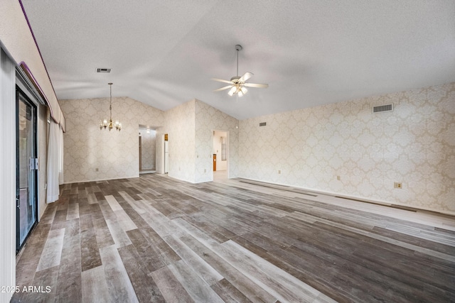 unfurnished living room featuring hardwood / wood-style flooring, a textured ceiling, lofted ceiling, and ceiling fan with notable chandelier