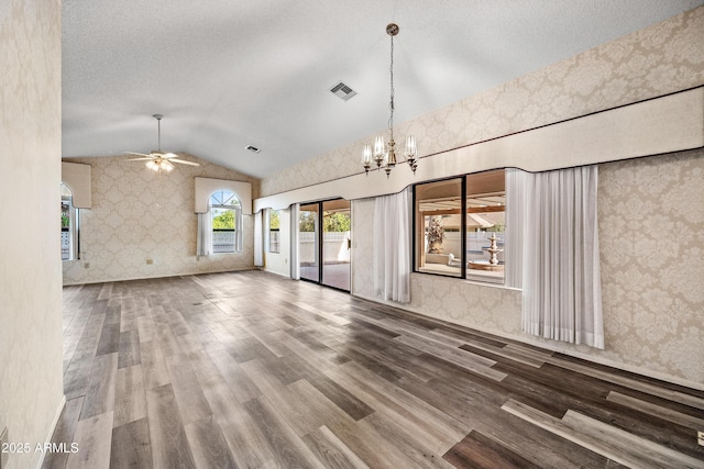 unfurnished living room featuring ceiling fan with notable chandelier, wood-type flooring, and lofted ceiling