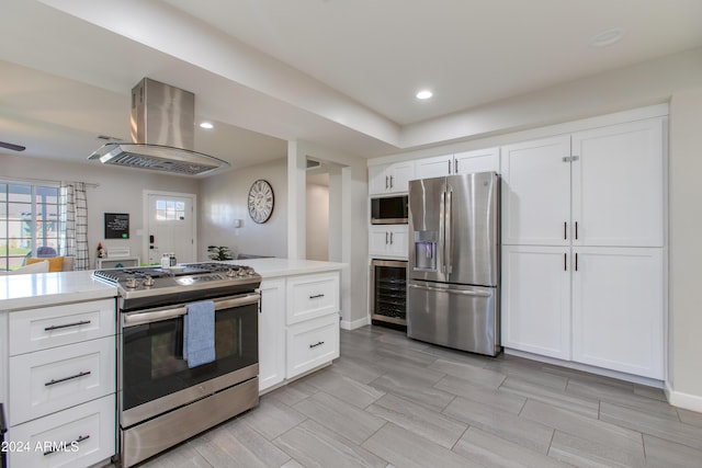 kitchen with appliances with stainless steel finishes, white cabinetry, beverage cooler, and range hood