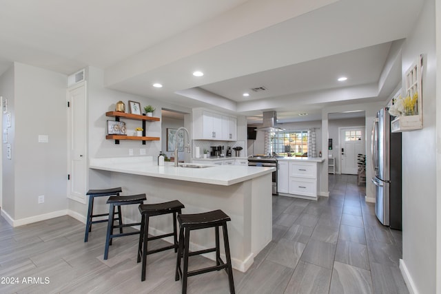 kitchen with kitchen peninsula, a breakfast bar, white cabinets, and stainless steel appliances