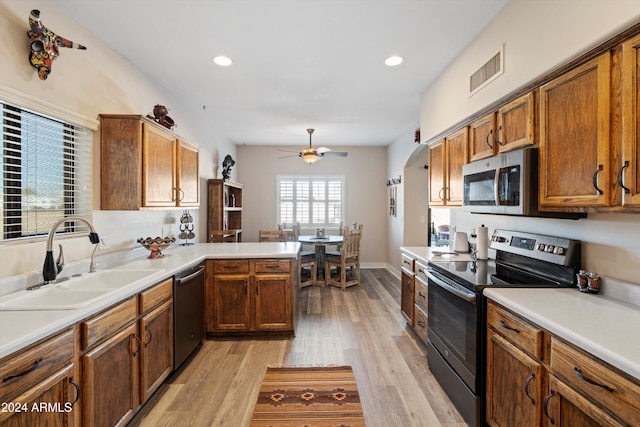 kitchen featuring kitchen peninsula, sink, light hardwood / wood-style floors, and appliances with stainless steel finishes