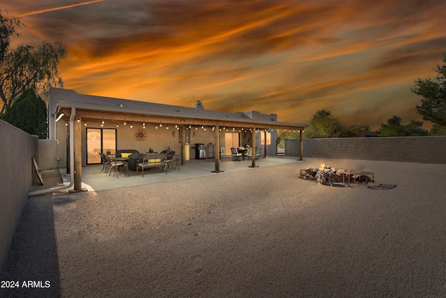 back house at dusk featuring a patio area and a fire pit