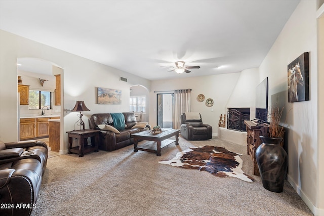 living room featuring ceiling fan, sink, light colored carpet, and plenty of natural light