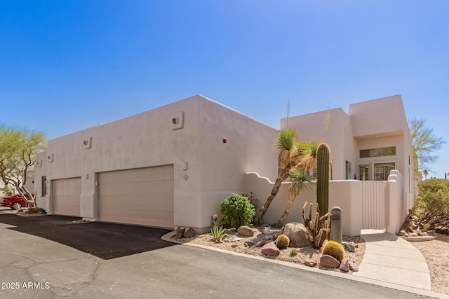 view of front of property featuring stucco siding, an attached garage, and aphalt driveway