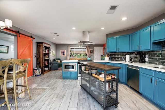 1027 E El Camino Dr, Phoenix, AZ 85020 - kitchen featuring appliances with stainless steel finishes, blue cabinetry, island exhaust hood, a barn door, and recessed lighting