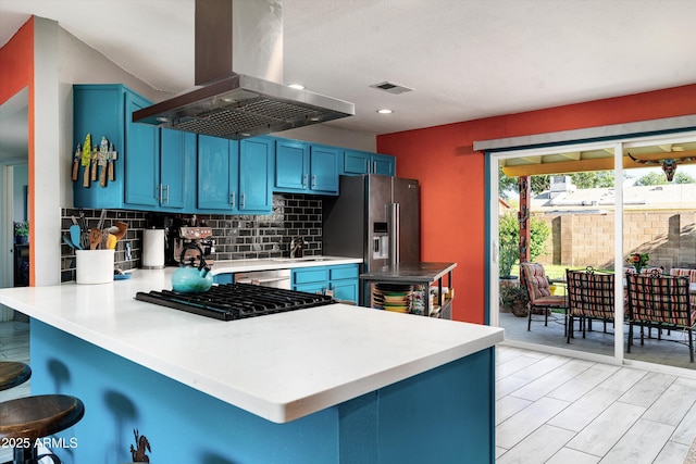 1027 E El Camino Dr, Phoenix, AZ 85020 - kitchen with island exhaust hood, blue cabinetry, a peninsula, a kitchen breakfast bar, and tasteful backsplash