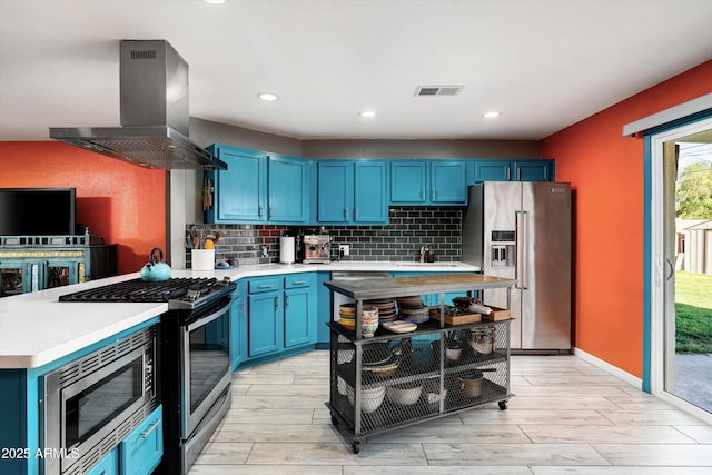 1027 E El Camino Dr, Phoenix, AZ 85020 - kitchen featuring appliances with stainless steel finishes, blue cabinetry, island exhaust hood, light countertops, and tasteful backsplash