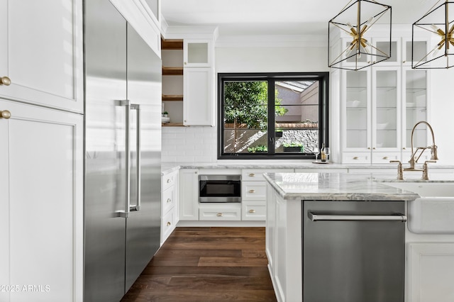 kitchen with light stone countertops, white cabinets, built in appliances, tasteful backsplash, and dark hardwood / wood-style floors