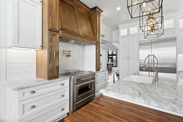 kitchen with custom exhaust hood, tasteful backsplash, white cabinetry, sink, and high quality appliances