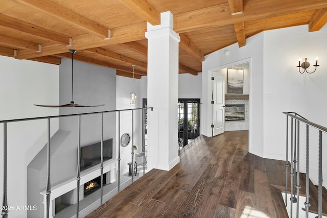 hall with dark wood-type flooring, ornate columns, beam ceiling, and wood ceiling