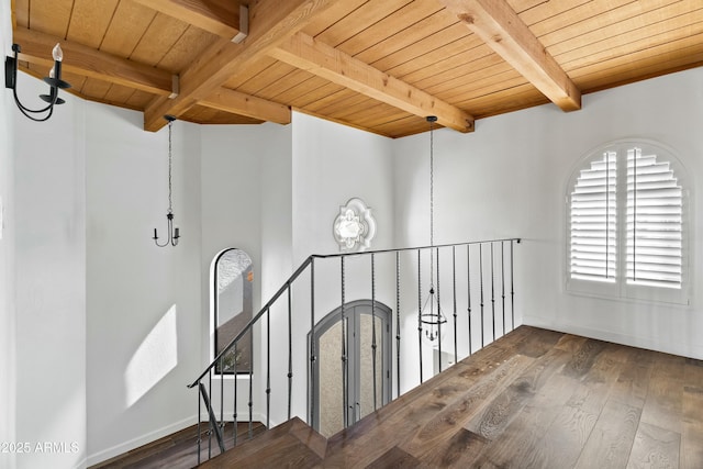 hallway with a notable chandelier, beam ceiling, dark wood-type flooring, and wooden ceiling