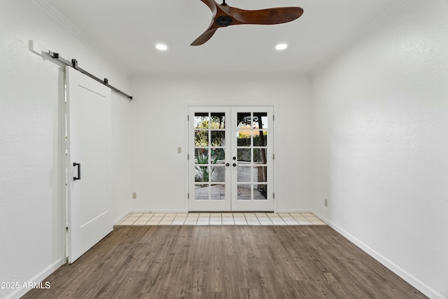 spare room with hardwood / wood-style floors, crown molding, a barn door, french doors, and ceiling fan