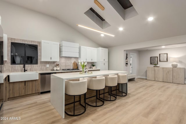 kitchen featuring appliances with stainless steel finishes, a center island, white cabinetry, sink, and backsplash